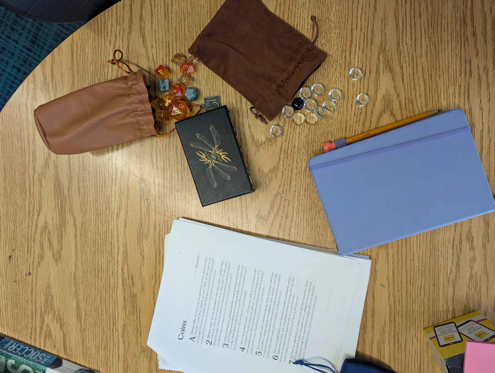 My materials for teaching Koriko: glass stones, a tarot deck, dice, a journal, and lots and lots of printed packets