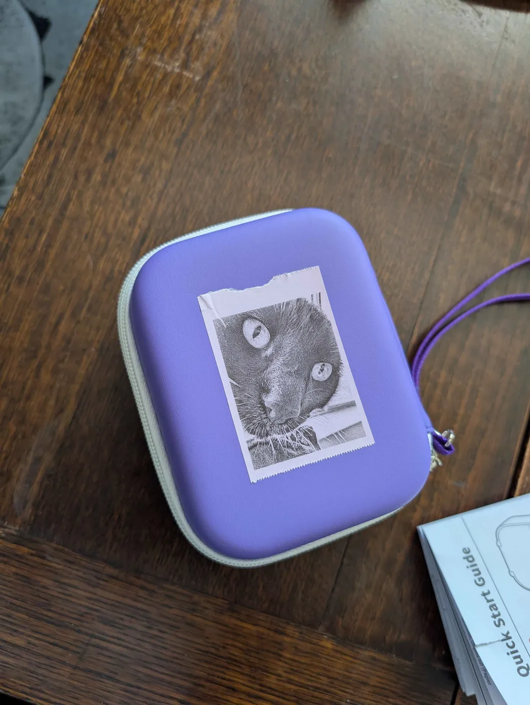 A purple sticker printer box with a printed sticker of a cat's face on it